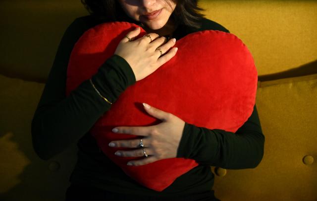 FILED - 02 January 2026, Berlin: A woman holds a heart-shaped cushion in her arms. Valentine's Day, also known as the Day of Love, is celebrated annually on February 14. Photo: Elisa Schu/dpa