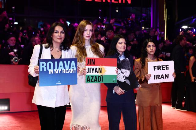 12 February 2026, Berlin: (L-R) Human rights activist Duezen Tekkal, actress Pheline Roggan, and actress Jasmin Tabatabai hold up signs reading "Free Iran" and "Rojava" on the red carpet in front of the Berlinale Palast, on the opening night of the 76th Berlin International Film Festival. Photo: Christoph Soeder/dpa