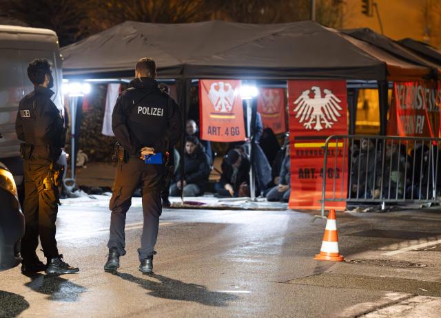 12 February 2026, Hesse, Frankfurt/Main: Men and women pray under a pavilion set up on the street in front of the closed Imam Ali Mosque in Frankfurt. By displaying protest posters and referring to the fourth article of the Basic Law, the gathering under the slogan "Defend religious freedom: Hands off our mosque" is considered an approved protest action according to the administrative court. Photo: Boris Roessler/dpa