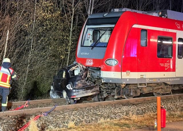 13 February 2026, Bavaria, Höhenkirchen-Siegertsbrunn: A wrecked car sits in front of a commuter train in Höhenkirchen-Siegertsbrunn following an accident. Photo: Vifogra/Friedrich/dpa
