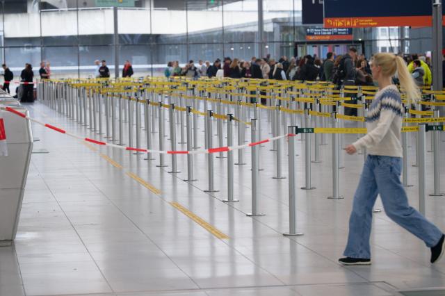 13 February 2026, North Rhine-Westphalia, Cologne: A woman walks through the nearly empty hall of Cologne/Bonn Airport, where flight operations were largely suspended due to a security incident. The airport is expected to reopen fully shortly. Photo: Henning Kaiser/dpa