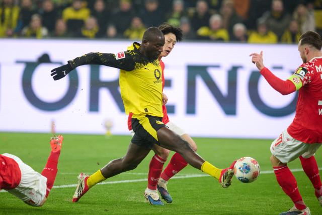 13 February 2026, North Rhine-Westphalia, Dortmund: Dortmund's Serhou Guirassy and Mainz' Jae-sung Lee battle for the ball during the German Bundesliga soccer match between Borussia Dortmund and FSV Mainz 05 at Sgina Iduna Park. Photo: Bernd Thissen/dpa - IMPORTANT NOTE: In accordance with the regulations of the DFL German Football League and the DFB German Football Association, it is prohibited to utilize or have utilized photographs taken in the stadium and/or of the match in the form of sequential images and/or video-like photo series.