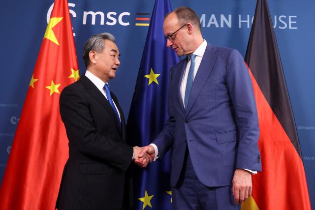 14 February 2026, Bavaria, Munich: German Chancellor Friedrich Merz (R) shakes hands with Chinese Foreign Minister Wang Yi for a joint meeting on the sidelines of the Munich Security Conference. Photo: Thilo Schmuelgen/Reuters/Pool/dpa