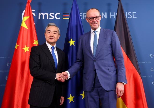 14 February 2026, Bavaria, Munich: German Chancellor Friedrich Merz (R) shakes hands with Chinese Foreign Minister Wang Yi for a joint meeting on the sidelines of the Munich Security Conference. Photo: Thilo Schmuelgen/Reuters/Pool/dpa