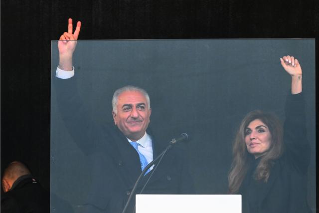 14 February 2026, Bavaria, Munich: Reza Pahlavi, son of the deposed Iranian Shah Mohammad Reza Pahlavi, stands with his wife Yasmine Pahlavi on stage at the Theresienwiese during a demonstration under the slogan  "Human rights and freedom in Iran. International solidarity with the Iranian people", on the sidelines of the 62nd Munich Security Conference (MSC). Photo: Felix Hörhager/dpa