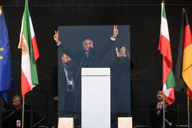 14 February 2026, Bavaria, Munich: Reza Pahlavi, son of the deposed Iranian Shah Mohammad Reza Pahlavi, stands with his wife Yasmine Pahlavi on stage at the Theresienwiese during a demonstration under the slogan  "Human rights and freedom in Iran. International solidarity with the Iranian people", on the sidelines of the 62nd Munich Security Conference (MSC). Photo: Felix Hörhager/dpa