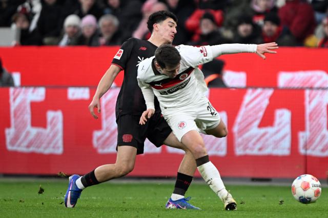 14 February 2026, North Rhine-Westphalia, Leverkusen: Leverkusen's Ibrahim Maza and St. Pauli's Mathias Rasmussen battle for the ball during the German Bundesliga soccer match between Bayer Leverkusen and FC St. Pauli at BayArena. Photo: Federico Gambarini/dpa - IMPORTANT NOTE: In accordance with the regulations of the DFL German Football League and the DFB German Football Association, it is prohibited to utilize or have utilized photographs taken in the stadium and/or of the match in the form of sequential images and/or video-like photo series.