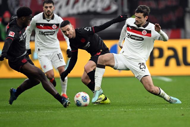 14 February 2026, North Rhine-Westphalia, Leverkusen: Leverkusen's Ernest Poku and St. Pauli's Adam DZwigala battle for the ball during the German Bundesliga soccer match between Bayer Leverkusen and FC St. Pauli at BayArena. Photo: Federico Gambarini/dpa - IMPORTANT NOTE: In accordance with the regulations of the DFL German Football League and the DFB German Football Association, it is prohibited to utilize or have utilized photographs taken in the stadium and/or of the match in the form of sequential images and/or video-like photo series.