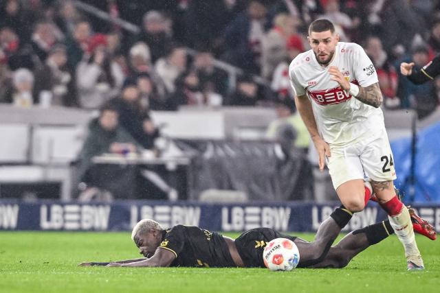 14 February 2026, Baden-Württemberg, Stuttgart: Cologne's Ragnar Ache and Stuttgart's Jeff Chabot battle for the ball during the German Bundesliga soccer match between VfB Stuttgart and 1. FC Cologne at MHPArena. Photo: Harry Langer/dpa - IMPORTANT NOTE: In accordance with the regulations of the DFL German Football League and the DFB German Football Association, it is prohibited to utilize or have utilized photographs taken in the stadium and/or of the match in the form of sequential images and/or video-like photo series.
