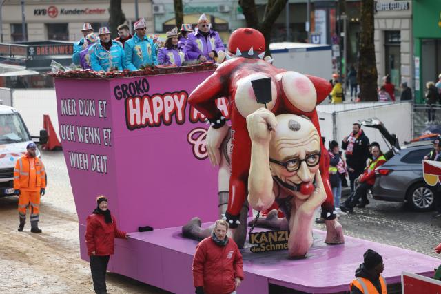 16 February 2026, North Rhine-Westphalia, Cologne: A float showing German Chancellor Merz and Finance Minister Klingbeil in a sado-maso government show takes part in the Rose Monday parade in Cologne. Rose Monday on the Rhine is the highlight of the Rhineland carnival season with its traditional parades. Photo: Oliver Berg/dpa