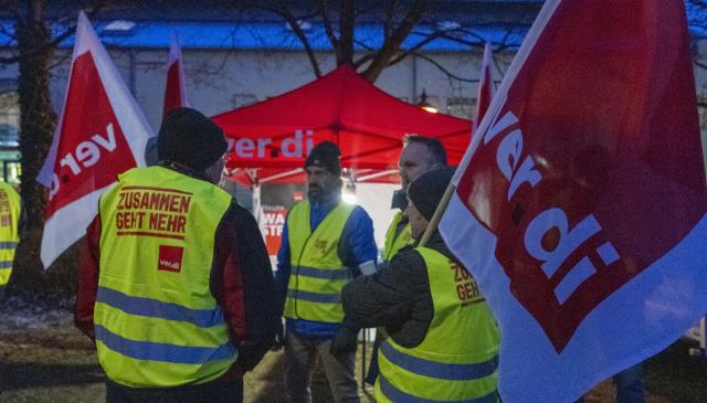 19 February 2026, Bavaria, Augsburg: Transport workers holding Verdi union flags and wearing high-visibility vests as they participate in an all-day warning strike. Photo: Stefan Puchner/dpa