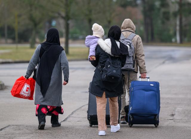 FILED - 13 March 2025, Brandenburg, Eisenhuettenstadt: Migrants leave the premises of Brandenburg's Central Immigration Office (ZABH) with luggage. Photo: Patrick Pleul/dpa