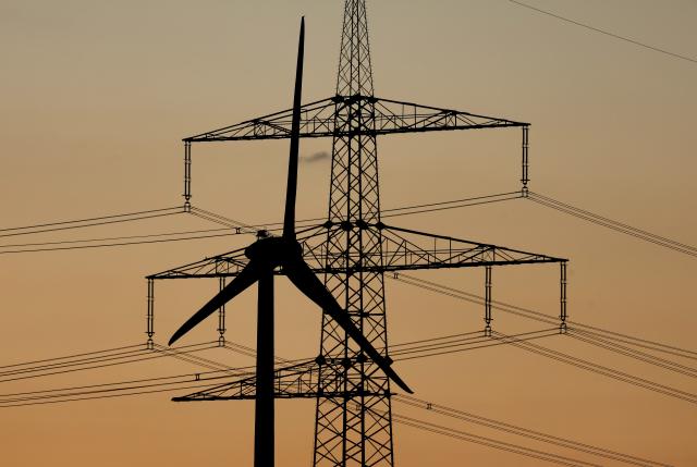 FILED - 24 August 2025, Bavaria, Sommerhausen: A wind turbine stands in front of an electricity pylon at sunset. The International Energy Agency (IEA) does not intend to be dissuaded from its commitment to combating climate change despite pressure from the United States, as the organization seeks to expand its capabilities on critical raw materials. Photo: Karl-Josef Hildenbrand/dpa