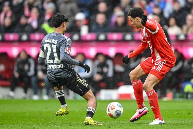21 February 2026, Bavaria, Munich: Bayern Munich's Jamal Musiala (R) and Eintracht Frankfurt's Nathaniel Brown battle for the ball during the German Bundesliga soccer match between Bayern Munich and Eintracht Frankfurt at Allianz Arena. Photo: Harry Langer/dpa - WICHTIGER HINWEIS: Gemäß den Vorgaben der DFL Deutsche Fußball Liga bzw. des DFB Deutscher Fußball-Bund ist es untersagt, in dem Stadion und/oder vom Spiel angefertigte Fotoaufnahmen in Form von Sequenzbildern und/oder videoähnlichen Fotostrecken zu verwerten bzw. verwerten zu lassen.