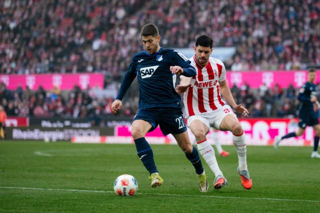 21 February 2026, North Rhine-Westphalia, Cologne: Cologne's Cenk Oezkacar (R) and Hoffenheim's Andrej Kramaric battle for the ball during the German Bundesliga soccer match between 1. FC Cologne and TSG 1899 Hoffenheim at RheinEnergieStadion. Photo: Marius Becker/dpa - WICHTIGER HINWEIS: Gemäß den Vorgaben der DFL Deutsche Fußball Liga bzw. des DFB Deutscher Fußball-Bund ist es untersagt, in dem Stadion und/oder vom Spiel angefertigte Fotoaufnahmen in Form von Sequenzbildern und/oder videoähnlichen Fotostrecken zu verwerten bzw. verwerten zu lassen.