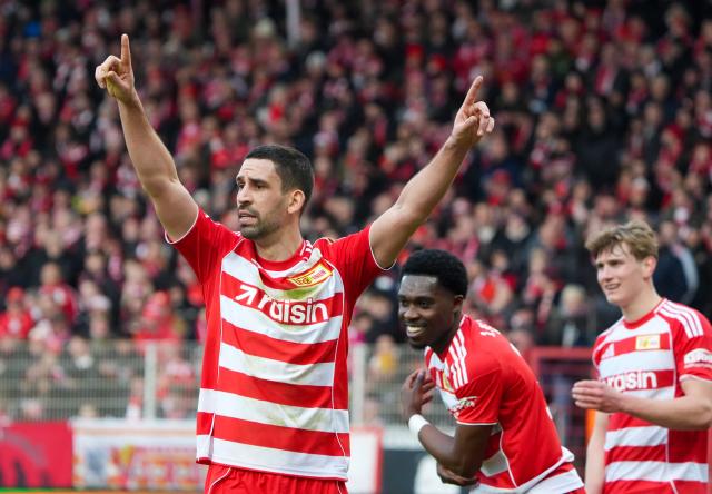 21 February 2026, Berlin: Union Berlin's Rani Khedira (L) celebrates scoring his side's first goal with teammates Ilyas Ansah (C) and Aljoscha Kemlein during the German Bundesliga soccer match between 1. FC Union Berlin and Bayer Leverkusen at An der Alten Försterei. Photo: Soeren Stache/dpa - WICHTIGER HINWEIS: Gemäß den Vorgaben der DFL Deutsche Fußball Liga bzw. des DFB Deutscher Fußball-Bund ist es untersagt, in dem Stadion und/oder vom Spiel angefertigte Fotoaufnahmen in Form von Sequenzbildern und/oder videoähnlichen Fotostrecken zu verwerten bzw. verwerten zu lassen.