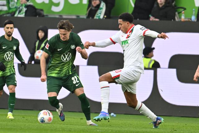 21 February 2026, Lower Saxony, Wolfsburg: Wolfsburg's Mattias Svanberg (L) and Augsburg's Noahkai Banks battle for the ball during the German Bundesliga soccer match between VfL Wolfsburg and FC Augsburg at Volkswagen Arena. Photo: Swen Pförtner/dpa - WICHTIGER HINWEIS: Gemäß den Vorgaben der DFL Deutsche Fußball Liga bzw. des DFB Deutscher Fußball-Bund ist es untersagt, in dem Stadion und/oder vom Spiel angefertigte Fotoaufnahmen in Form von Sequenzbildern und/oder videoähnlichen Fotostrecken zu verwerten bzw. verwerten zu lassen.