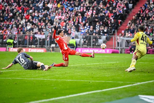 21 February 2026, Bavaria, Munich: Bayern Munich's Jamal Musiala (C) in action against Eintracht Frankfurt's Hugo Larsson (L) and goalkeeper Kaua Santos during the German Bundesliga soccer match between Bayern Munich and Eintracht Frankfurt at Allianz Arena. Photo: Harry Langer/dpa - WICHTIGER HINWEIS: Gemäß den Vorgaben der DFL Deutsche Fußball Liga bzw. des DFB Deutscher Fußball-Bund ist es untersagt, in dem Stadion und/oder vom Spiel angefertigte Fotoaufnahmen in Form von Sequenzbildern und/oder videoähnlichen Fotostrecken zu verwerten bzw. verwerten zu lassen.