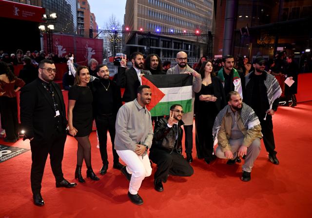 21 February 2026, Berlin: The team of the film "Chronicles from the Siege" holds a Palestinian flag as they arrive for the Berlinale Award Ceremony of the 76th Berlin International Film Festival. Photo: Sebastian Christoph Gollnow/dpa