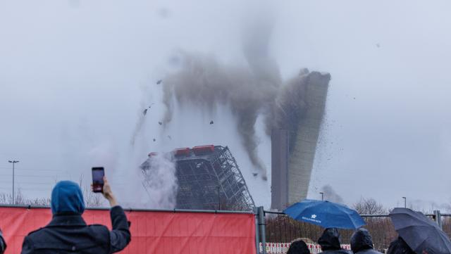 22 February 2026, North Rhine-Westphalia, Ibbenbüren: A view during the blasting and demolition of the 275-meter-high chimney of the former coal-fired power plant in Ibbenbueren. The Hagedorn company is currently demolishing everything that belonged to the old power plant. Electricity grid operator Amprion will build a converter station on the site, which will be used to feed electricity from wind power in the north into the grid. Photo: David Ebener/dpa
