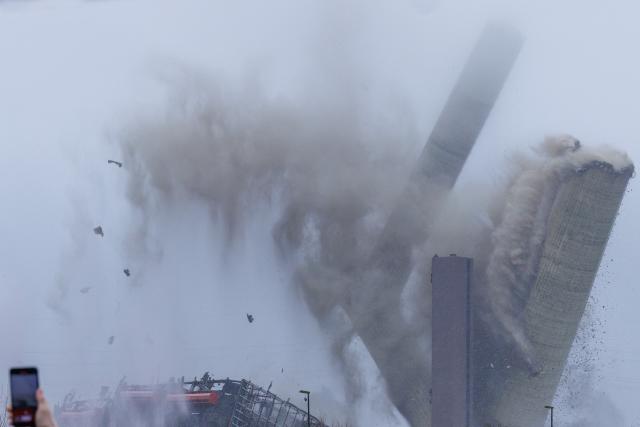 22 February 2026, North Rhine-Westphalia, Ibbenbüren: A view during the blasting and demolition of the 275-meter-high chimney of the former coal-fired power plant in Ibbenbueren. The Hagedorn company is currently demolishing everything that belonged to the old power plant. Electricity grid operator Amprion will build a converter station on the site, which will be used to feed electricity from wind power in the north into the grid. Photo: David Ebener/dpa