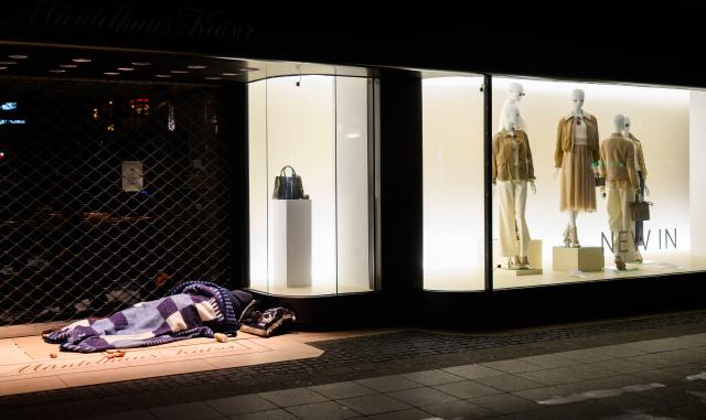23 February 2026, Lower Saxony, Hanover: A homeless person sleeps mext to the entrance of a fashion store in Hanover's city center. Photo: Julian Stratenschulte/dpa