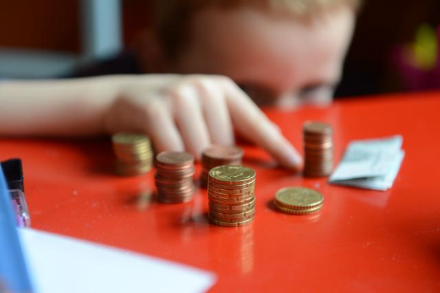 FILED - 10 April 2012, Berlin: A five-year-old boy counts money on a table. Photo: Jens Kalaene/dpa-Zentralbild/dpa