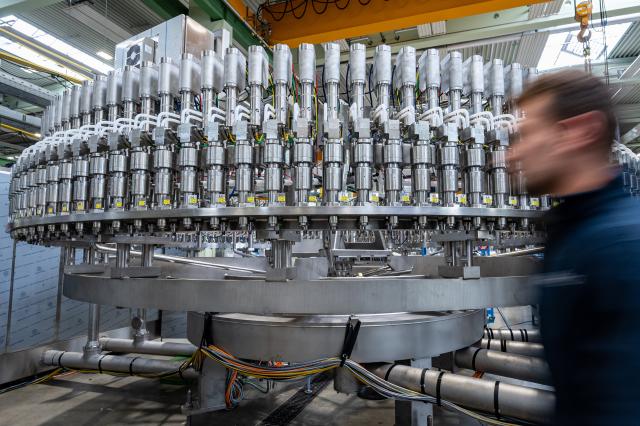 FILED - 25 April 2022, Neutraubling: An employee walks past a filling line in the production department of a mechanical engineering company. Photo: Armin Weigel/dpa