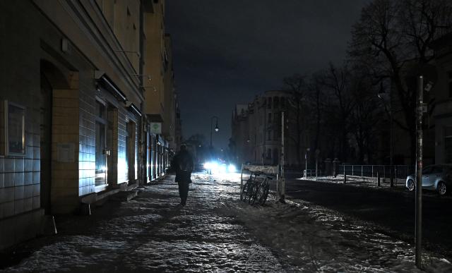 FILED - 06 January 2026, Berlin: A person walks down a dark street in Zehlendorf, lit only by a car headlight during a power outage in Berlin. Photo: Elisa Schu/dpa