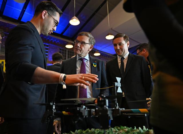 23 February 2026, Berlin: German Foreign Minister Johann Wadephul inspects a drone at Cafe Kyiv with Matthias Lehna (L) and Bogdan Miftakhov (R). Four years into the war in Ukraine, the Konrad Adenauer Foundation hosts the event for political, academic, and cultural figures. Photo: Markus Lenhardt/dpa