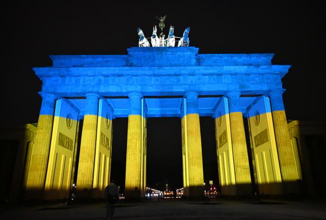 24 February 2026, Berlin: The Brandenburg Gate is illuminated in the colors of the Ukraine flag as participants gather to mark the fourth anniversary of the outbreak of the war in Ukraine. Photo: Markus Lenhardt/dpa