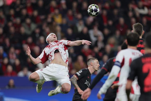 24 February 2026, North Rhine-Westphalia, Leverkusen: Olympiacos Piraeus' Lorenzo Pirola (L) and Bayer Leverkusen's Alejandro Grimaldo battle for the ball during the UEFA Champions League knockout phase play offs, second leg soccer match between Bayer Leverkusen and Olympiacos Piraeus at BayArena. Photo: Rolf Vennenbernd/dpa