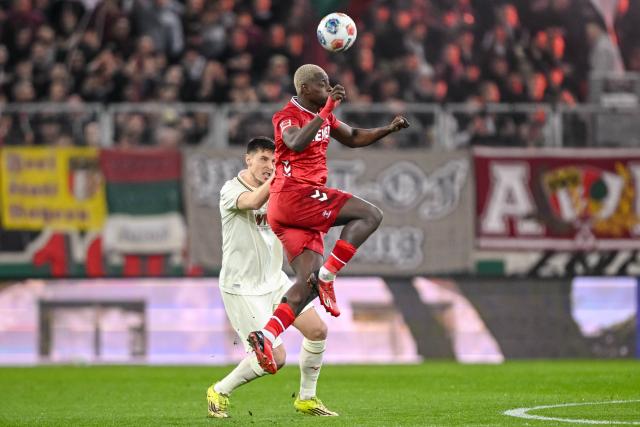 27 February 2026, Bavaria, Augsburg: Augsburg's Keven Schlotterbeck (L) and Cologne's Ragnar Ache
battle for the ball during the German Bundesliga soccer match between FC Augsburg and 1. FC Cologne at the WWK Arena. Photo: Harry Langer/dpa - WICHTIGER HINWEIS: Gemäß den Vorgaben der DFL Deutsche Fußball Liga bzw. des DFB Deutscher Fußball-Bund ist es untersagt, in dem Stadion und/oder vom Spiel angefertigte Fotoaufnahmen in Form von Sequenzbildern und/oder videoähnlichen Fotostrecken zu verwerten bzw. verwerten zu lassen.