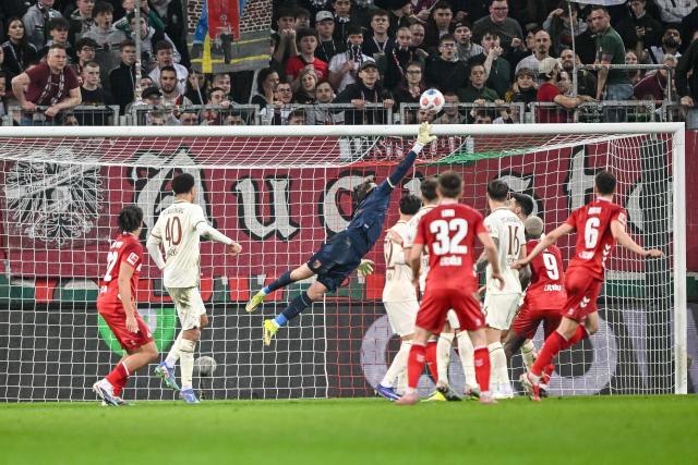 27 February 2026, Bavaria, Augsburg: Augsburg goalkeeper Finn Dahmen clears Augsburg's Jeffrey Gouweleeuw's header over the bar during the German Bundesliga soccer match between FC Augsburg and 1. FC Cologne at the WWK Arena. Photo: Harry Langer/dpa - WICHTIGER HINWEIS: Gemäß den Vorgaben der DFL Deutsche Fußball Liga bzw. des DFB Deutscher Fußball-Bund ist es untersagt, in dem Stadion und/oder vom Spiel angefertigte Fotoaufnahmen in Form von Sequenzbildern und/oder videoähnlichen Fotostrecken zu verwerten bzw. verwerten zu lassen.