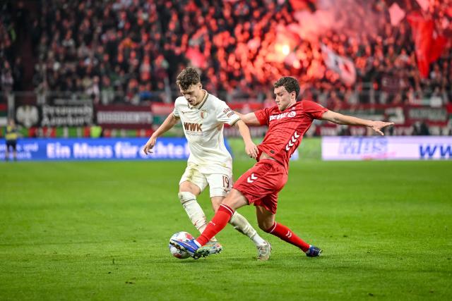 27 February 2026, Bavaria, Augsburg: Augsburg's Robin Fellhauer (L) and Cologne's Luca Waldschmidt battle for the ball during the German Bundesliga soccer match between FC Augsburg and 1. FC Cologne at the WWK Arena. Photo: Harry Langer/dpa - WICHTIGER HINWEIS: Gemäß den Vorgaben der DFL Deutsche Fußball Liga bzw. des DFB Deutscher Fußball-Bund ist es untersagt, in dem Stadion und/oder vom Spiel angefertigte Fotoaufnahmen in Form von Sequenzbildern und/oder videoähnlichen Fotostrecken zu verwerten bzw. verwerten zu lassen.