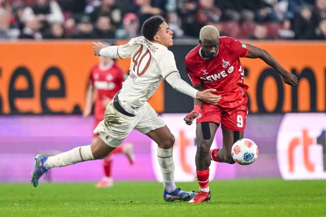 27 February 2026, Bavaria, Augsburg: Augsburg's Noahkai Banks (L) and Cologne's Ragnar Ache battle for the ball during the German Bundesliga soccer match between FC Augsburg and 1. FC Cologne at the WWK Arena. Photo: Harry Langer/dpa - WICHTIGER HINWEIS: Gemäß den Vorgaben der DFL Deutsche Fußball Liga bzw. des DFB Deutscher Fußball-Bund ist es untersagt, in dem Stadion und/oder vom Spiel angefertigte Fotoaufnahmen in Form von Sequenzbildern und/oder videoähnlichen Fotostrecken zu verwerten bzw. verwerten zu lassen.