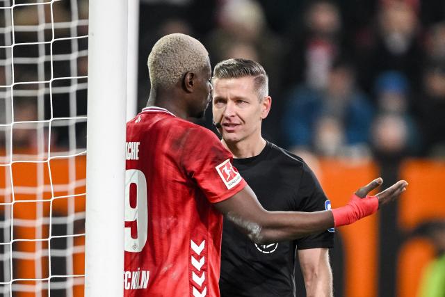 27 February 2026, Bavaria, Augsburg: Cologne's Ragnar Ache (L) and referee Tobias Welz discuss during the German Bundesliga soccer match between FC Augsburg and 1. FC Cologne at the WWK Arena. Photo: Harry Langer/dpa - WICHTIGER HINWEIS: Gemäß den Vorgaben der DFL Deutsche Fußball Liga bzw. des DFB Deutscher Fußball-Bund ist es untersagt, in dem Stadion und/oder vom Spiel angefertigte Fotoaufnahmen in Form von Sequenzbildern und/oder videoähnlichen Fotostrecken zu verwerten bzw. verwerten zu lassen.