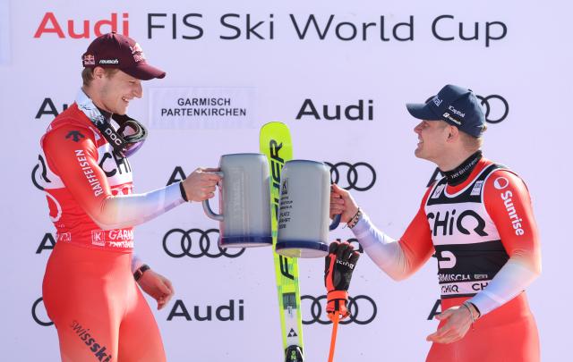 28 February 2026, Bavaria, Garmisch-Partenkirchen: Switzerland's winner Marco Odermatt (L) and third-placed compatriot Stefan Rogentin celebrate during the the award ceremony after the downhill competition of the Men's Alpine skiing World Cup, . Photo: Karl-Josef Hildenbrand/dpa