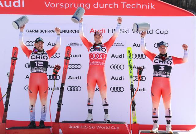 28 February 2026, Bavaria, Garmisch-Partenkirchen: (L-R) Switzerland's second-placed Alexis Monney, winner Marco Odermatt and thied-placed Stefan Rogentin celebrate during the the award ceremony after the downhill competition of the Men's Alpine skiing World Cup, . Photo: Karl-Josef Hildenbrand/dpa