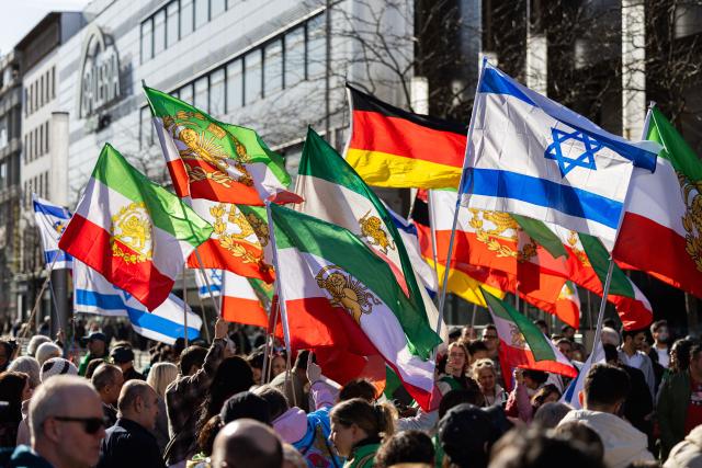 01 March 2026, Lower Saxony, Hanover: Demonstrators hold flags during a rally with the slogan "Human rights in Iran - solidarity with the civilian population" at Ernst-August-Platz in front of the main train station in Hanover. Photo: Michael Matthey/dpa