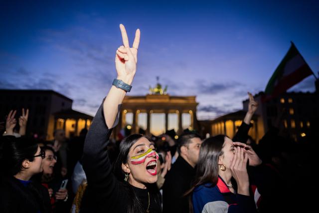 01 March 2026, Berlin: People celebrate the death of Iran's supreme leader, Ayatollah Khamenei during a protest under the slogan "Freedom for Iran under the leadership of Prince Reza Pahlavi" at the Brandenburg Gate. Photo: Christoph Soeder/dpa