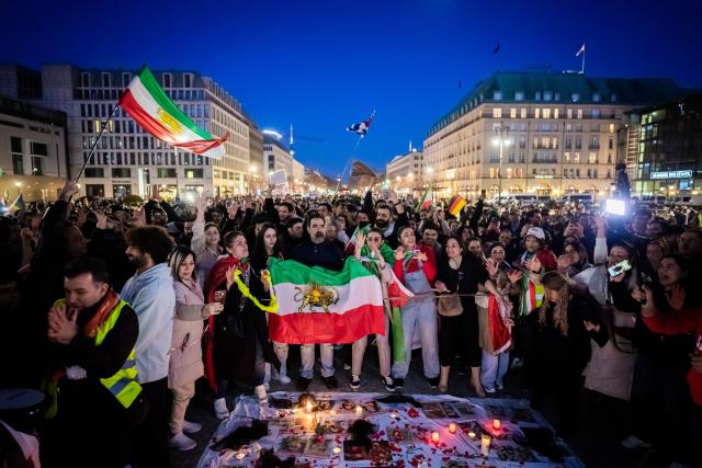01 March 2026, Berlin: People celebrate the death of Iran's supreme leader, Ayatollah Khamenei during a protest under the slogan "Freedom for Iran under the leadership of Prince Reza Pahlavi" at the Brandenburg Gate. Photo: Christoph Soeder/dpa