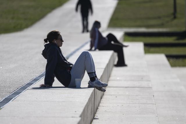 02 March 2026, Baden-Wuerttemberg, Boeblingen: A woman sits on a stone staircase in the sun. Photo: Marijan Murat/dpa