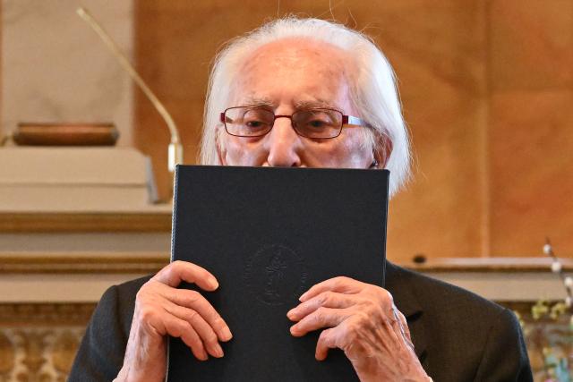 02 March 2026, Lower Saxony, Goettingen: Polish-Swedish Holocaust survivor Leon Weintraub kisses the honorary doctorate degree from Goettingen University Medical Center in the auditorium of Goettingen University. Photo: Swen Pförtner/dpa
