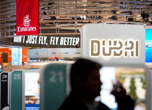 03 March 2026, Berlin: A man stands at the Dubai stand in Hall 2 on the opening day of the International Tourism Exchange (ITB). In the background is the Emirates stand with the slogan "Don't just fly, fly better". Photo: Soeren Stache/dpa