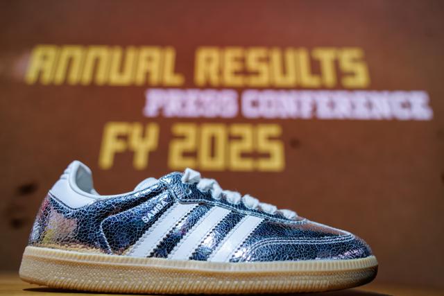 04 March 2026, Bavaria, Herzogenaurach: The logo and lettering of sports equipment manufacturer Adidas AG are prominently displayed on a shoe exhibited at the edge of the company's annual press conference. Photo: Daniel Karmann/dpa