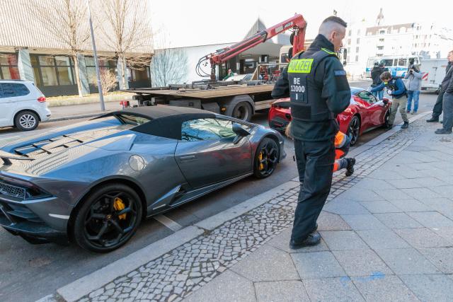 04 March 2026, Berlin: Police officers seize a Ferrari and a Lamborghini as police and tax investigators search several properties. Photo: Carsten Koall/dpa