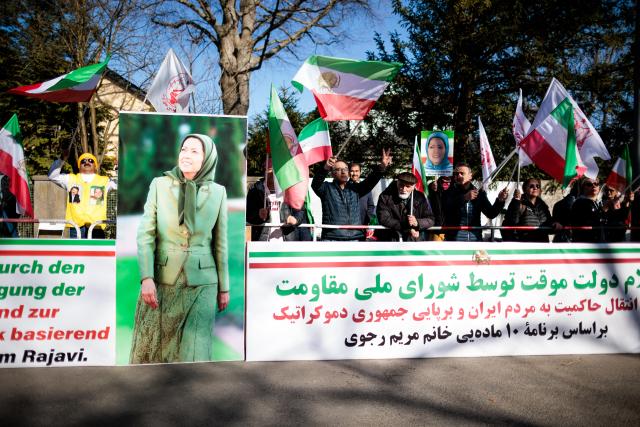 04 March 2026, Berlin: People wave the flags of Iran's national resistance behind various slogans and photos of Maryam Rajavi, the elected president of the National Council of Resistance of Iran, at a rally against the Iranian mullah regime in front of the Embassy of the Islamic Republic of Iran. Photo: Carsten Koall/dpa