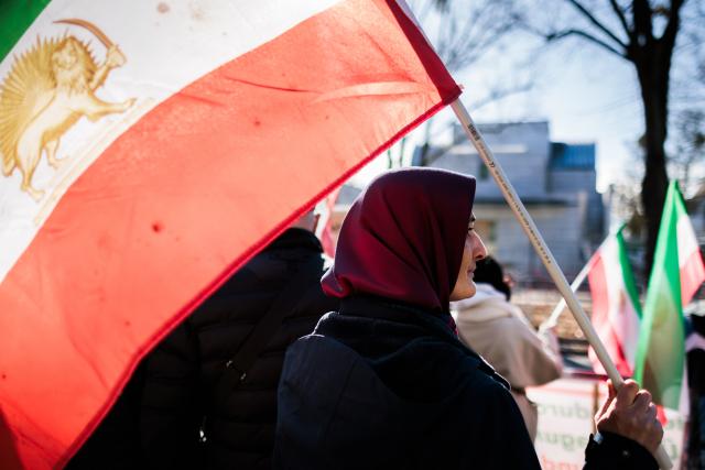 04 March 2026, Berlin: A woman waves the flag of Iran's national resistance at a rally against the Iranian mullah regime in front of the Embassy of the Islamic Republic of Iran in Berlin. Photo: Carsten Koall/dpa