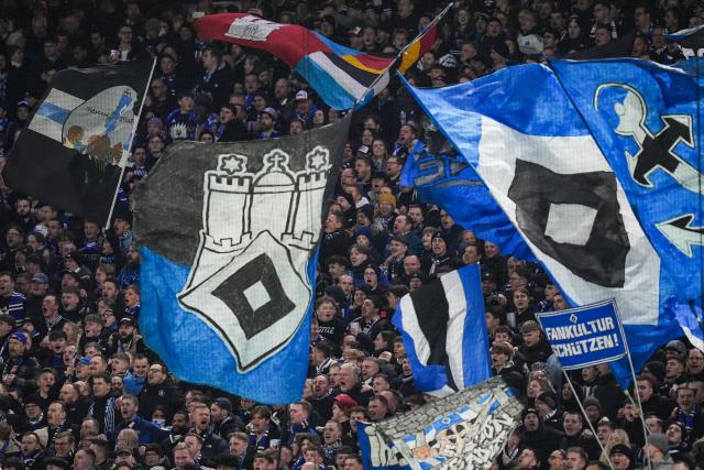 04 March 2026, Hamburg: Hamburg fans wave flags in the stands during the German Bundesliga soccer match between Hamburger SV and Bayer Leverkusen at the Volksparkstadion. Photo: Marcus Brandt/dpa - IMPORTANT NOTICE: DFL and DFB regulations prohibit any use of photographs as image sequences and/or quasi-video.